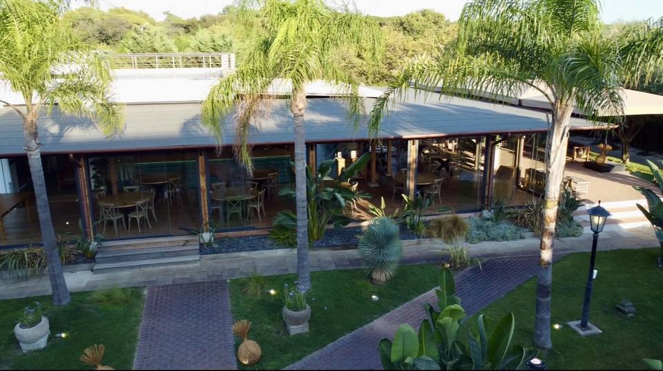 La veranda di MUY con i salotti in legno e il giardino sullo sfondo